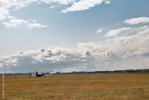 old soviet military plane stands on the airfield of grass. blue sky and clouds