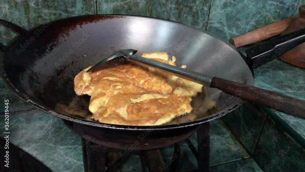 Old pan has hot oil and omelet, on the stove in rustic kitchen, dimly light, selective focus. Old pan has hot oil and omelet, on the stove in rustic kitchen, dimly light, selective focus.
