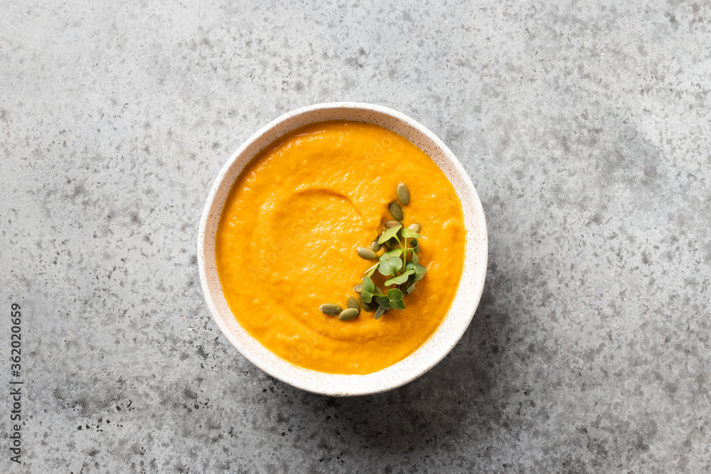 Pumpkin soup garnish microgreens on grey stone table. View from above. Minimal style. Pumpkin soup garnish microgreens on grey stone table. View from above. Minimal style.