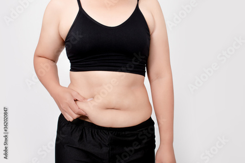 Asian women are overweight. She touched her excess belly fat. Isolated white background.