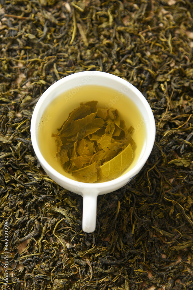 Cup of green tea and heap of dried organic tea leaves, dust and infuser Munnar, Kerala, India. Aromatic herbal Indian beverage for relaxation, stress relief. healthy drink has antioxidants, nutrients Cup of green tea and heap of dried organic tea leaves, dust and infuser Munnar, Kerala, India. Aromatic herbal Indian beverage for relaxation, stress relief. healthy drink has antioxidants, nutrients