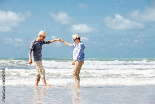 Happy  asian senior couple  dancing  on beach with blue sky background