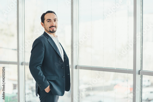 Photos Confident young businessman standing, keeping hands in pockets, looking at the camera, ready to hard work day