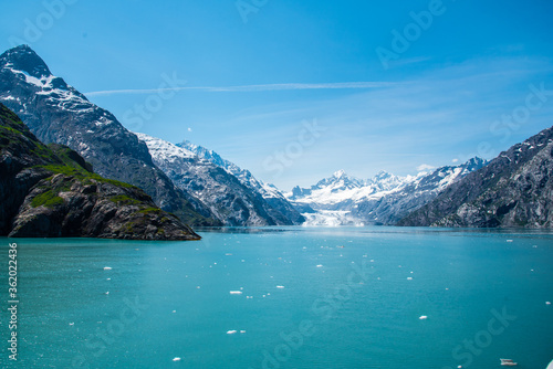 A distant view of Margerie Glacier, Alaska. Icebergs from the glacier are floating on the water surface in the foreground and snow capped mountains in the background. 