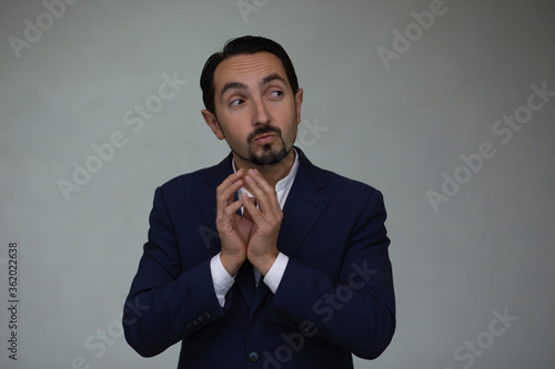 Bearded man is looking with suspicion expression, tapping his fingers.