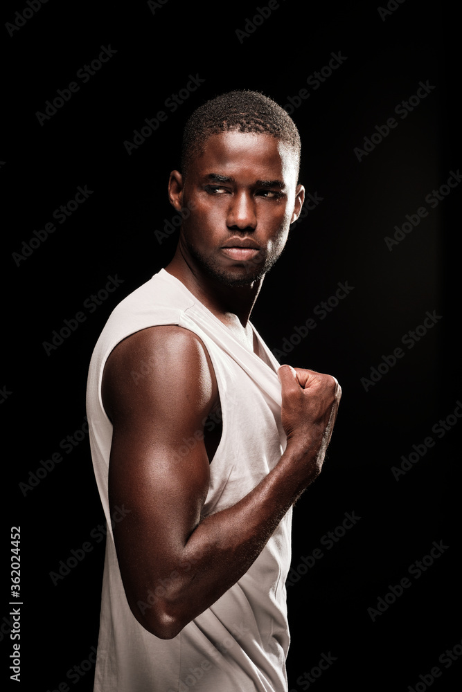 black man in profile position looking out camera wearing a white shirt and stretching his t-shirt