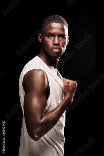 black man in profile position looking at camera wearing a white shirt and stretching his t-shirt