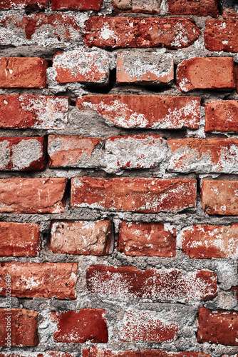 Texture of old brick wall with destroyed stucco. Vintage grunge red brick background closeup.