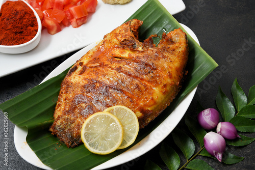 Kerala fish curry, Karimeen Pollichathu a popular hot and spicy baked fish in banana leaves Alleppey India.  pearl spot fish is marinated with Indian spices then wrapped in plantain leaf and grilled.  photo