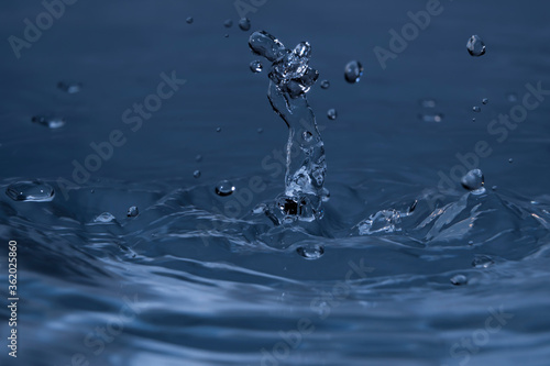 Splashing water drops causing wavy water surface and water column