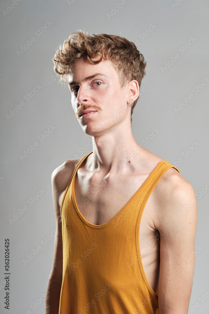 young blond boy with mustache and a yellow t-shirt wearing earrings standing looking at camera young blond boy with mustache and a yellow t-shirt wearing earrings standing looking at camera