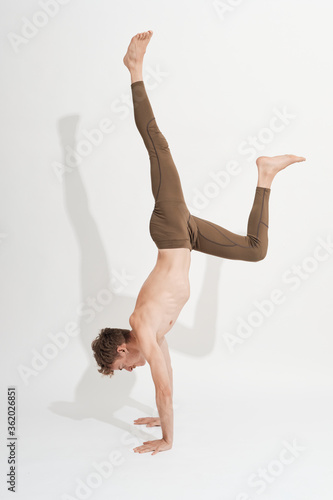 young blond boy handstanding on a white background