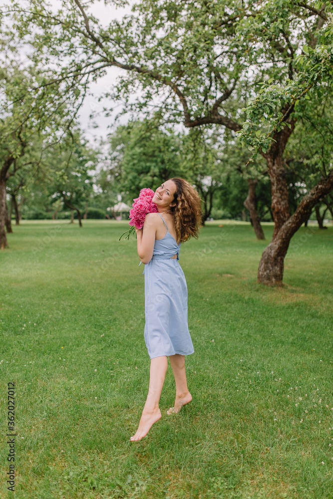 girl in the park with flowers peonies in a dress walks on the lawn girl in the park with flowers peonies in a dress walks on the lawn