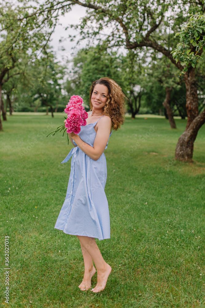 girl in the park with flowers peonies in a dress walks on the lawn girl in the park with flowers peonies in a dress walks on the lawn
