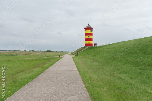 Leuchtturm hinter dem Deich in Pilsum an der deutschen Nordseeküste