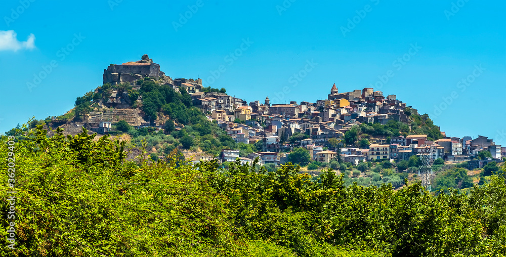 A view across the trees to the hilltop settlement of Castiglione di Sicilia in the foot hills of Mount Etna, Sicily in summer