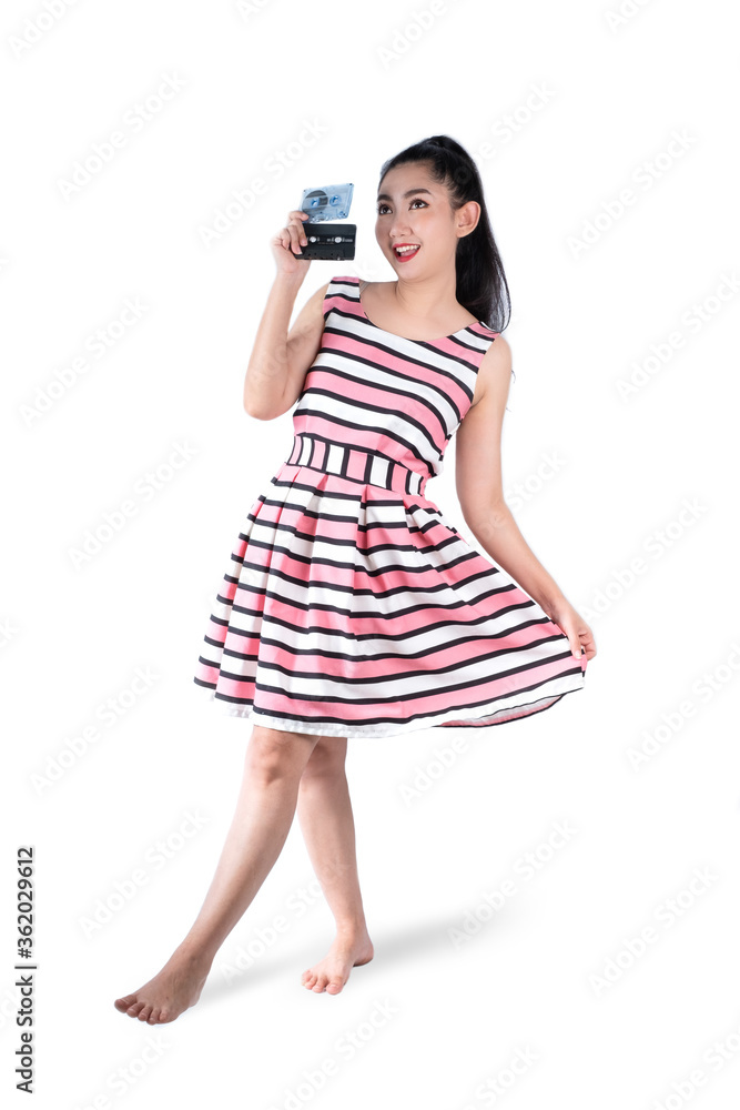 Full-length portrait young Asia woman in retro fashion pink dress holding a cassette tape on a white background Full-length portrait young Asia woman in retro fashion pink dress holding a cassette tape on a white background