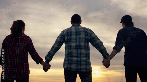 Teamwork. A group of people holding hands at sunset against the evening sky. The father son and daughter team reunited to achieve the goal.