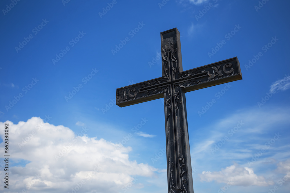 uplifted christian cross on a blue cloudy sky background