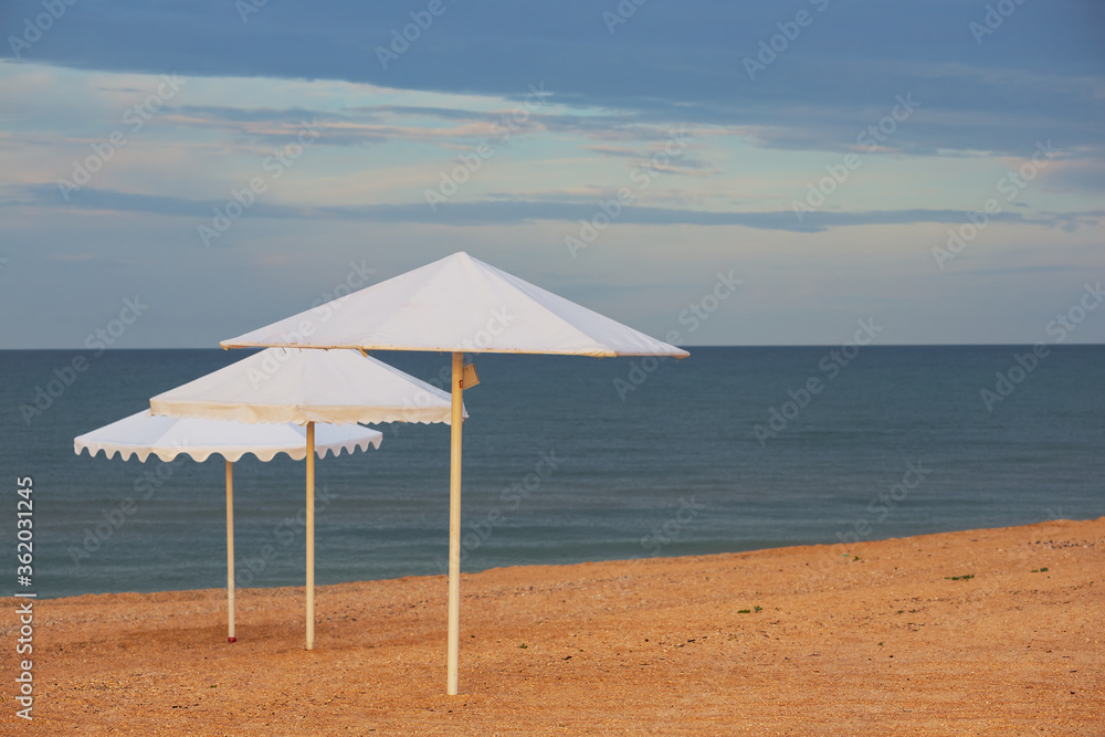 white sun umbrella on a sandy sea beach, summer sea vacation background