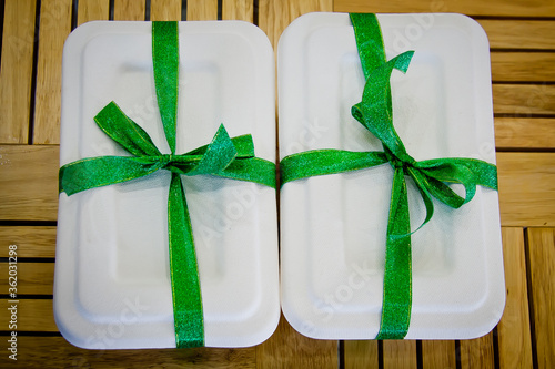 two white lunch boxes with green ribons photo