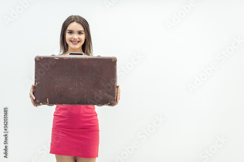 Young old-fashioned female in summer outfit sitting holding a retro suitcase ready for increadible vacations. photo