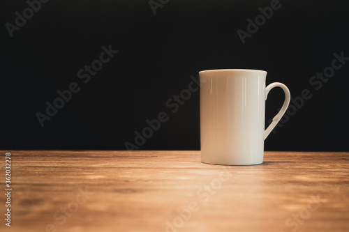 White coffee cup on wooden stand and black background, free space for your text