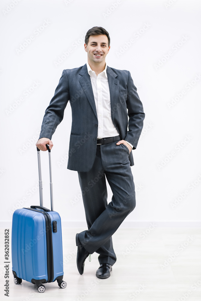 Full-length shot of the businessman holding a suitcase, hand in pocket, over white background. Full-length shot of the businessman holding a suitcase, hand in pocket, over white background.