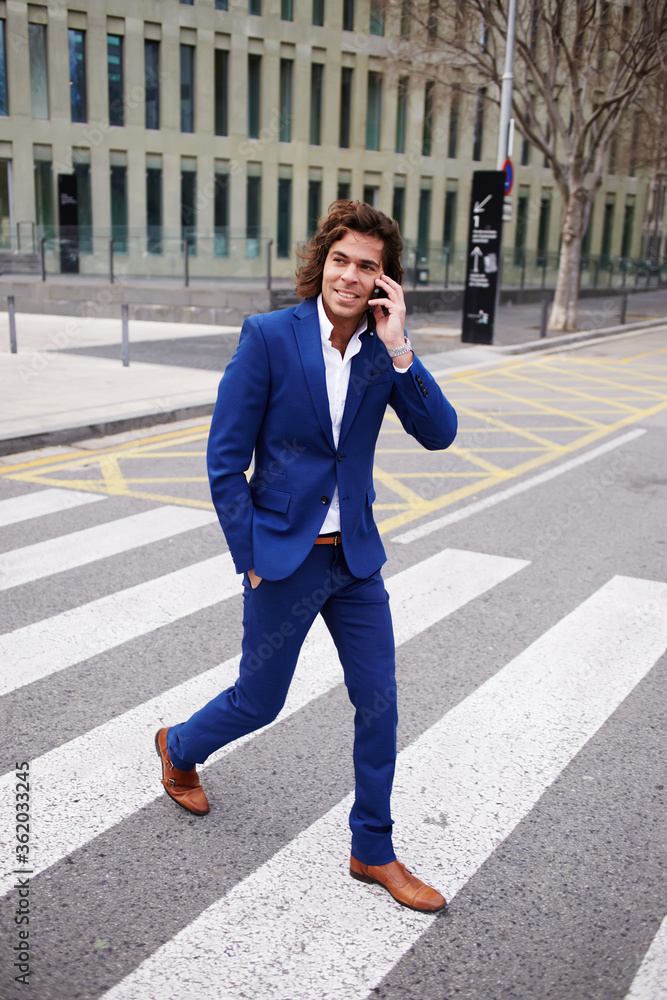 Full length portrait of a young businessman talking on his mobile phone while walking in the street Full length portrait of a young businessman talking on his mobile phone while walking in the street