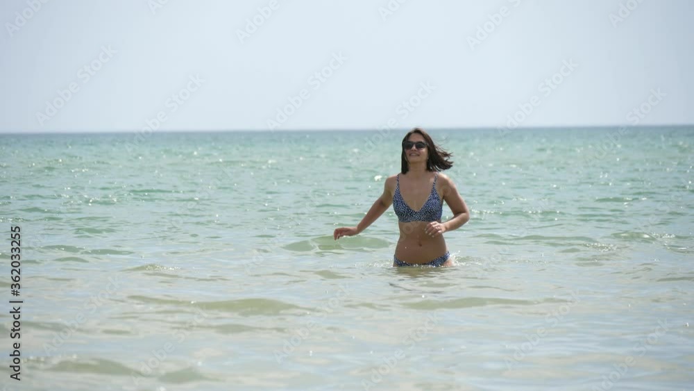 Beautiful girl in bikini and sunglasses running in the Black Sea in slow motion Beautiful girl in bikini and sunglasses running in the Black Sea in slow motion