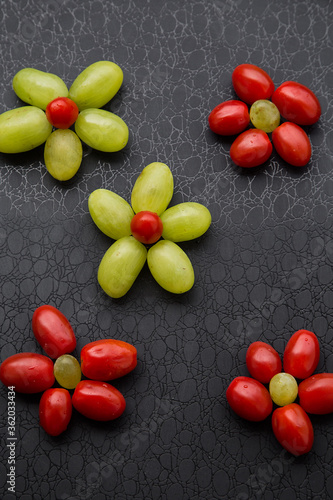 green grapes and cherry tomatoes in the form of flowers on a dark background