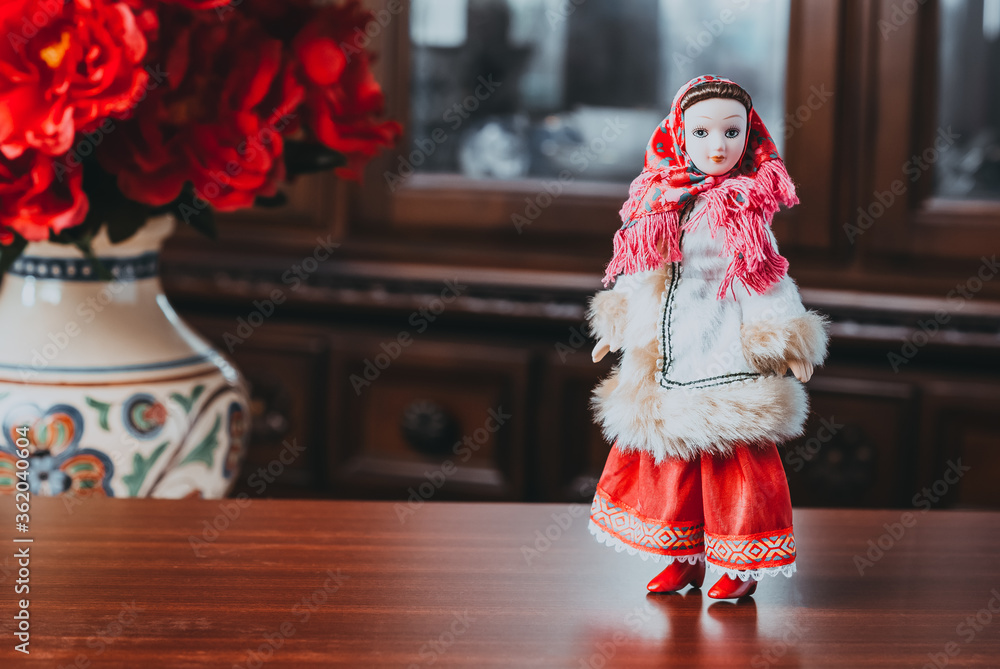 porcelain doll on table. ceramic toy doll in red shawl porcelain doll on table. ceramic toy doll in red shawl