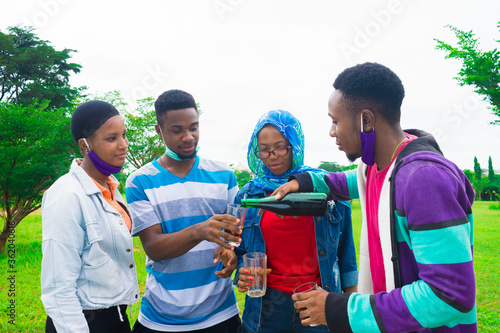 young black people standing in a park and pouring drinks into their glass cups