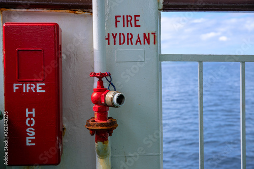 Fire hose and fire hydrant on ferry. Safety first on maritime vessel. Cargo or passenger shipping by sea.