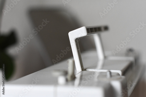 A fragment of a white electric sewing machine on a table in the scenery. Sews white cloth. Advertising sewing equipment. The controls of the sewing machine. Home crafts. Tailoring. 