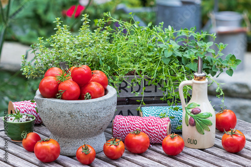 frische Tomanten im Mörser und frische Kräuter im Holzkasten