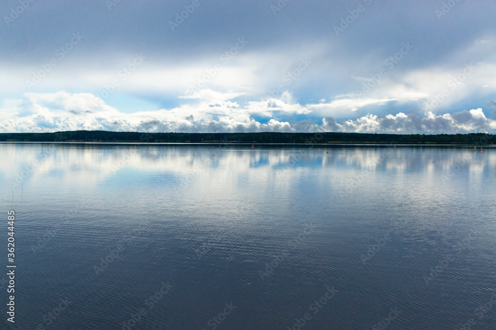 Landscape of a lake with sky with white and gray clouds. Natural background. landscape in gray-blue shades. 