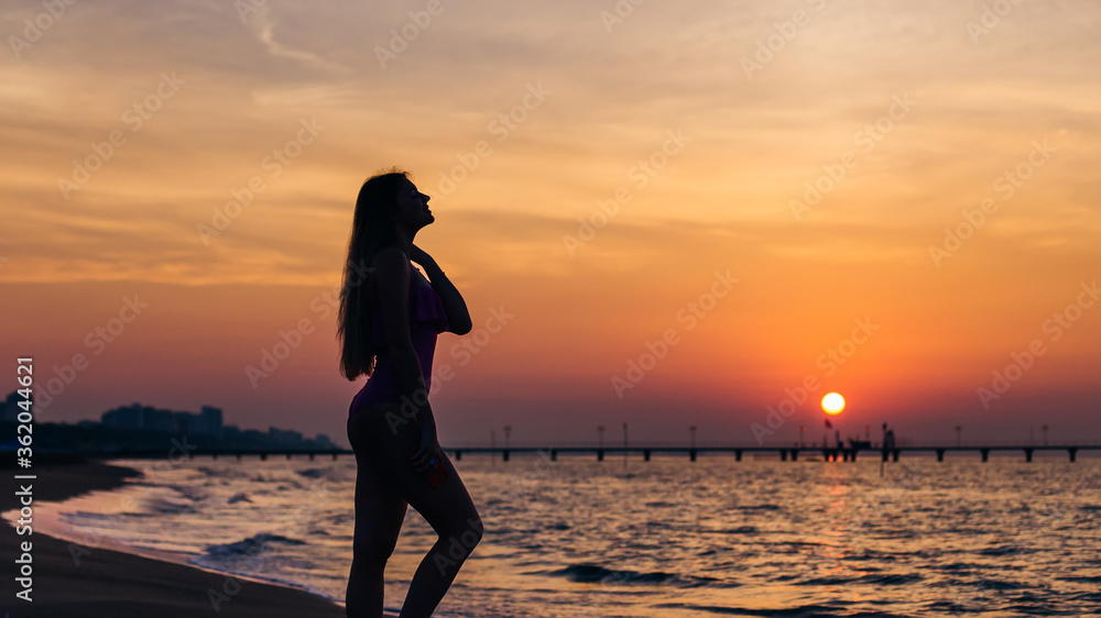 Fototapeta premium silhouette girl with long hair and fit body posing on the beach