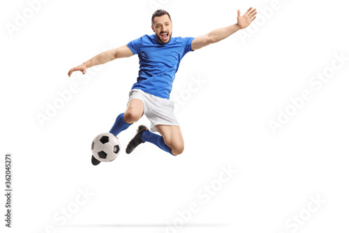 Footballer jumping and kicking a ball
