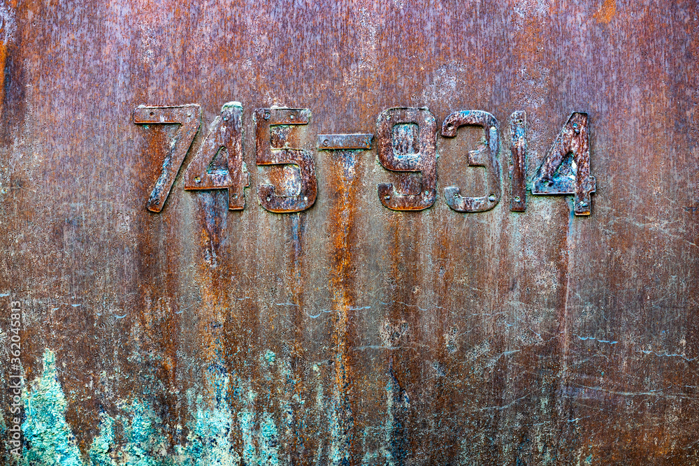Texture of old painted metal wall with a serial number. Corrosion and cracked rusty surface Texture of old painted metal wall with a serial number. Corrosion and cracked rusty surface