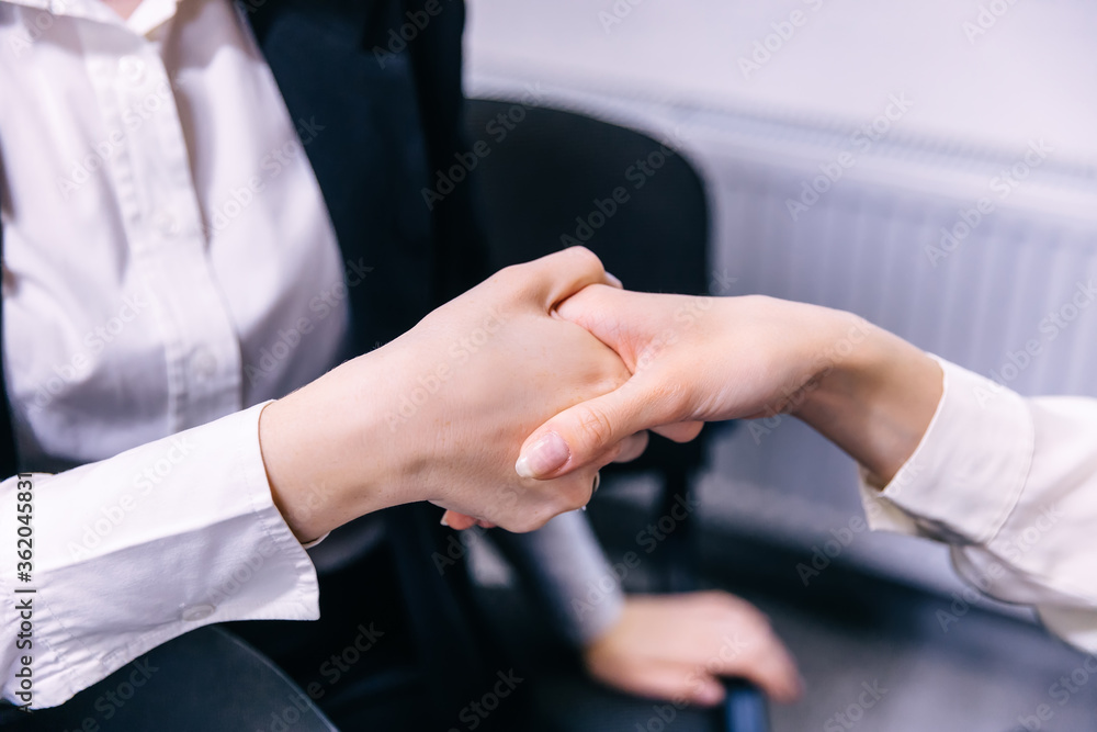 Obraz premium Two young businesswomen shake hands at the office. celebrating v