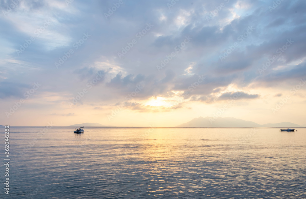 scenic view of cloudy sky,  sea and fishing boat at sunset