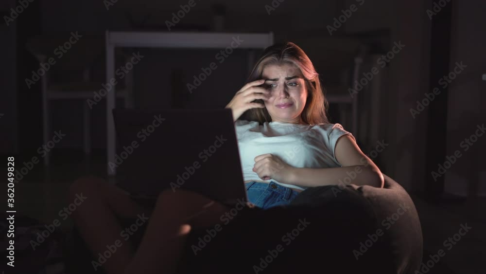 beautiful woman sitting on the couch while watching a horror movie TV at home in the evening. Scared girl watching tv on the living room. The concept of video games, entertainment, family, leisure beautiful woman sitting on the couch while watching a horror movie TV at home in the evening. Scared girl watching tv on the living room. The concept of video games, entertainment, family, leisure