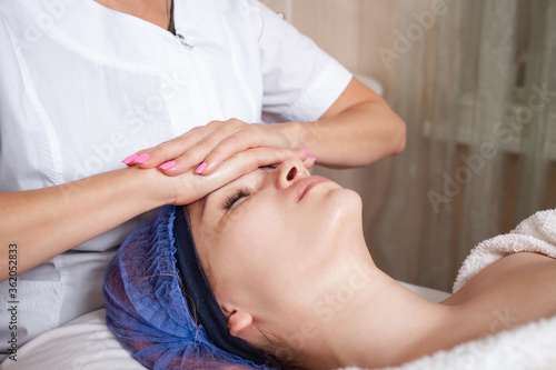 The beautician massages the face in the beauty salon. Improves blood flow, lymph outflow, increases skin elasticity, tones muscles, improves complexion, smooths wrinkles, reduces puffiness.