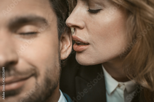 Foto Woman kisses or whispers in man's ear