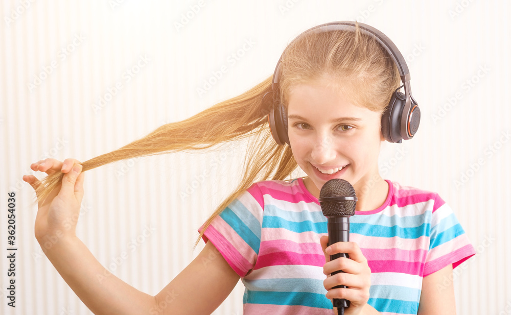 Smiling girl in headphones holding microphone in studio Smiling girl in headphones holding microphone in studio