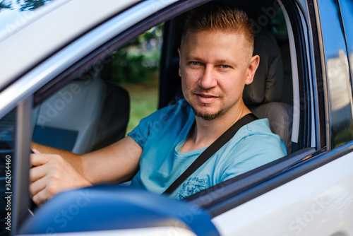 Young attractive driver in white car, outdoors