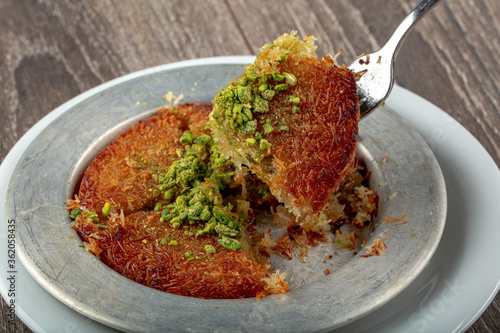 Turkish dessert kunefe, kunafa, kadayif with pistachio powder and cheese hot eaten a sweet. photo