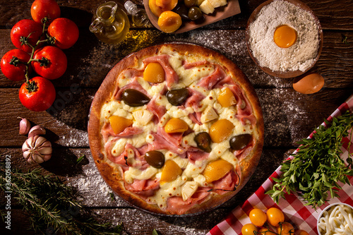 Sweet pizza with peaches, fig and pineapple on wood background. Top view, close up. Traditional Brazilian Pizza