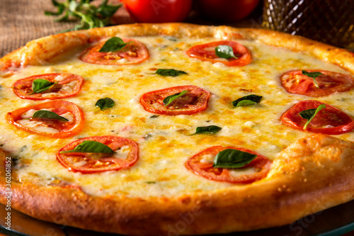 Pizza Margherita on wood background. Pizza Margarita with Tomatoes, Basil and Mozzarella Cheese close up. Traditional Brazilian Pizza.